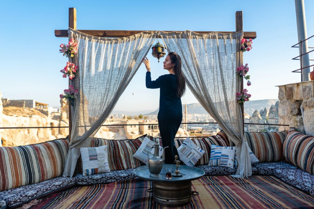 A woman arranges a lantern on a traditional Turkish terrace in Cappadocia, showcasing unique decor.