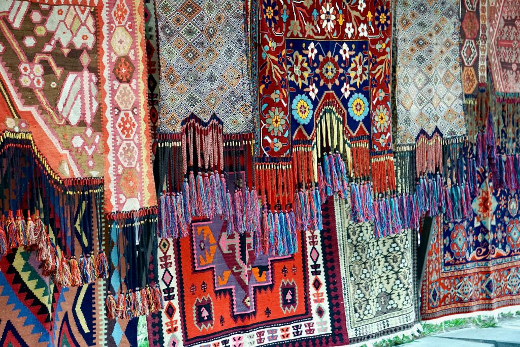 Vibrant display of traditional handmade rugs at a market showcasing intricate patterns and craftsmanship.