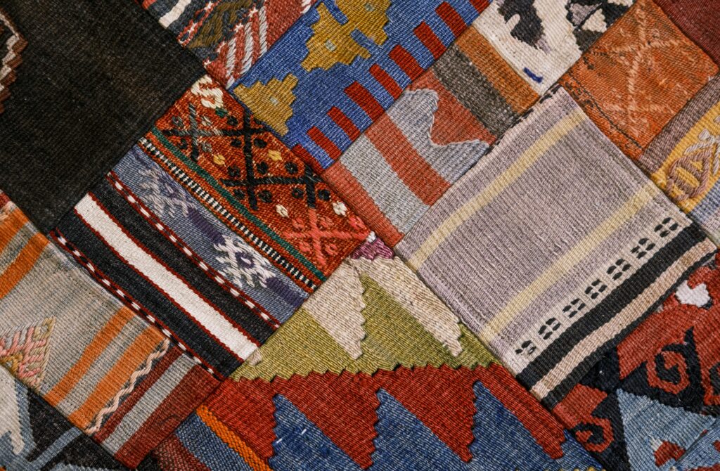 Intricate patchwork rug with geometric and multicolored traditional designs, showcasing rich textile craftsmanship.