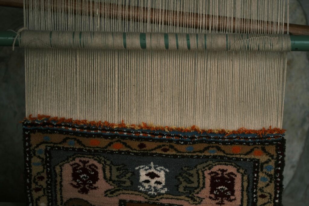 Detailed view of a handmade rug being woven on a traditional loom showcasing intricate patterns.