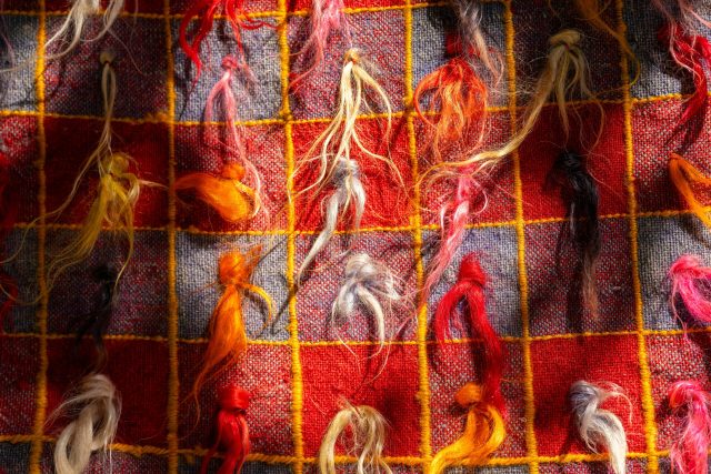 Vibrant close-up of a colorful, woven textile with frayed threads, showcasing detailed craftsmanship.