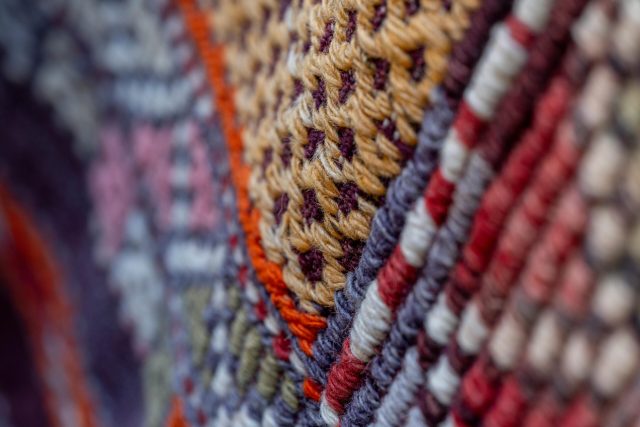 Detailed macro of colorful woven textile showing intricate patterns and textures.