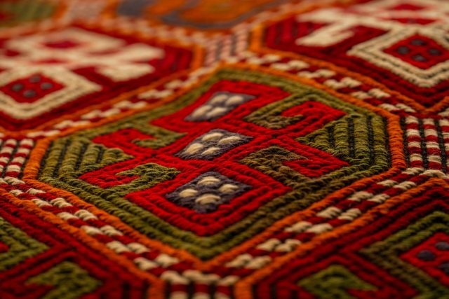 Close-up view of a colorful handwoven carpet with intricate patterns and textures from Antalya, Türkiye.
